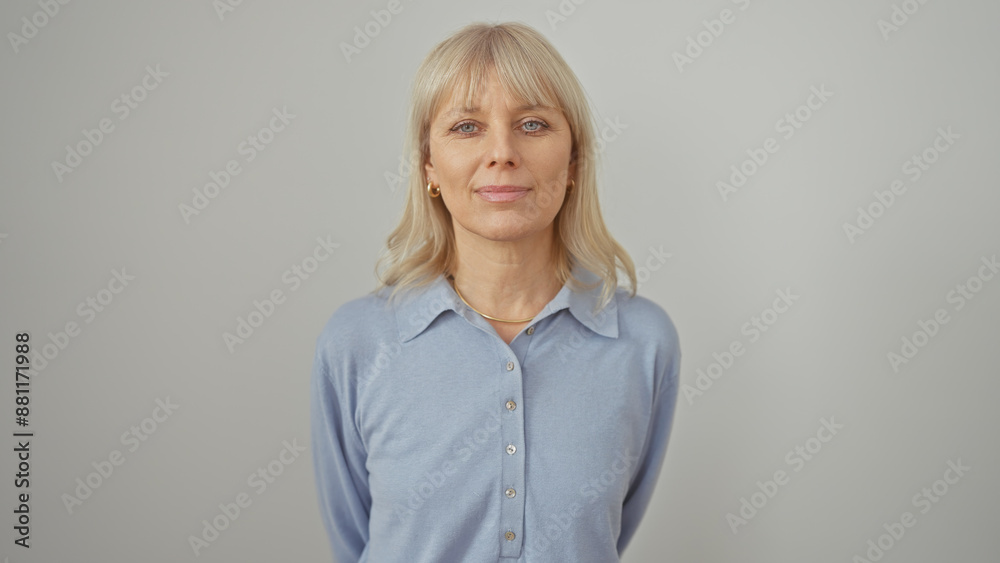 Serene mature woman with blonde hair wearing a blue shirt against a white background Serene mature woman with blonde hair wearing a blue shirt against a white background