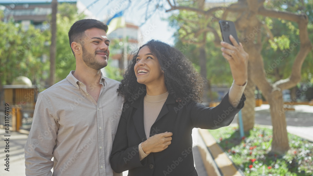 A happy couple takes a smiling selfie together in a sunny park with greenery. A happy couple takes a smiling selfie together in a sunny park with greenery.