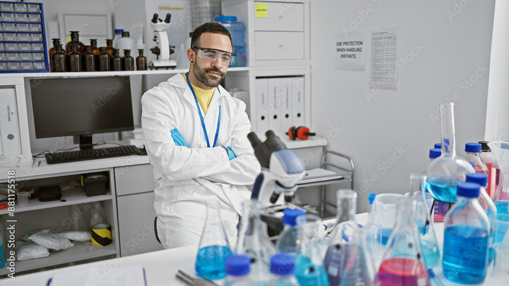 A bearded hispanic man in a white lab coat stands thoughtfully in a laboratory filled with scientific equipment. A bearded hispanic man in a white lab coat stands thoughtfully in a laboratory filled with scientific equipment.