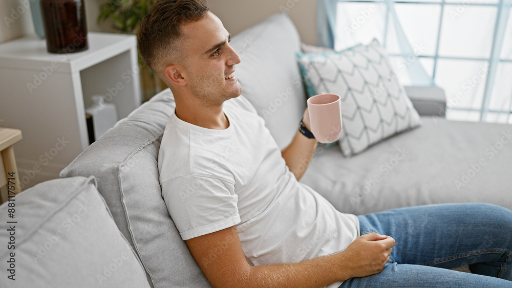 Smiling young hispanic man holding mug, relaxing on couch in a cozy living room setting Smiling young hispanic man holding mug, relaxing on couch in a cozy living room setting