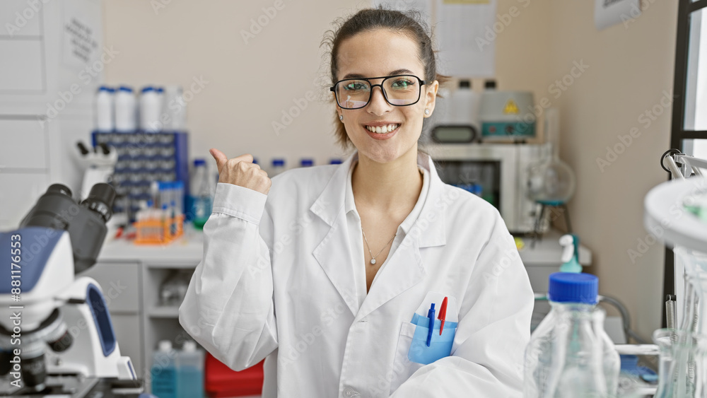 Smiling hispanic woman in lab coat gesturing thumb up in a laboratory setting, surrounded by scientific equipment. Smiling hispanic woman in lab coat gesturing thumb up in a laboratory setting, surrounded by scientific equipment.