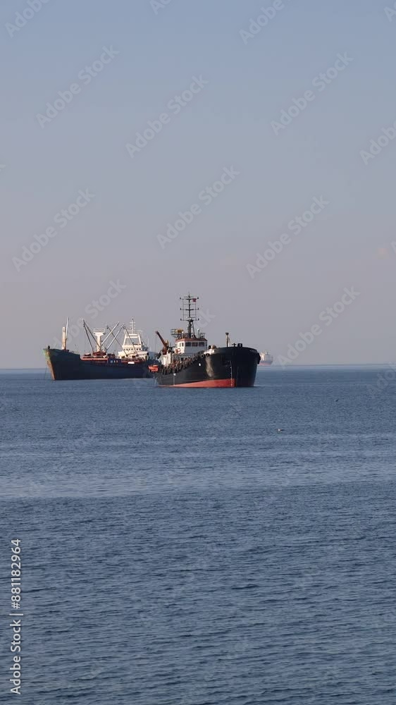 Solitary Cargo Ship Anchored in Calm Waters with Other Ships in the Distance Solitary Cargo Ship Anchored in Calm Waters with Other Ships in the Distance