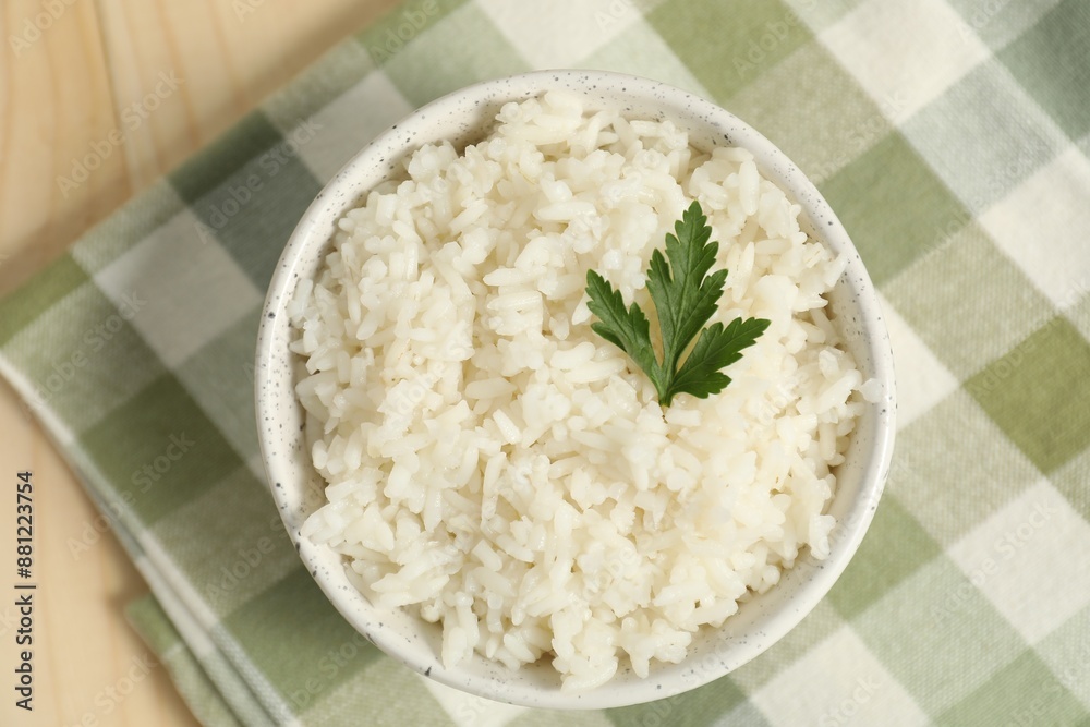 Delicious boiled rice in bowl and parsley on wooden table, top view Delicious boiled rice in bowl and parsley on wooden table, top view