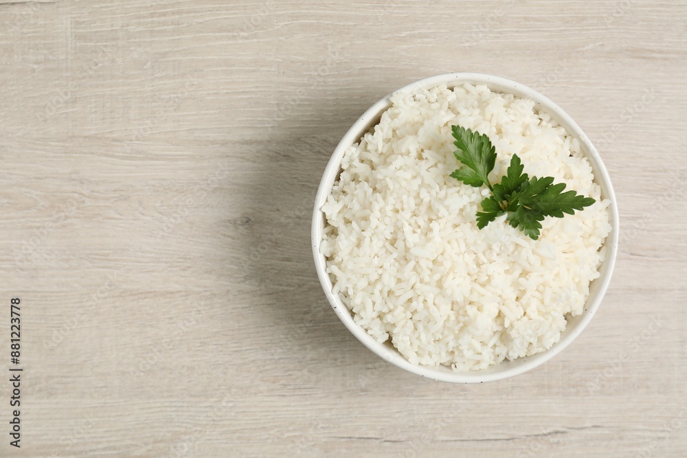 Delicious boiled rice in bowl and parsley on wooden table, top view. Space for text Delicious boiled rice in bowl and parsley on wooden table, top view. Space for text