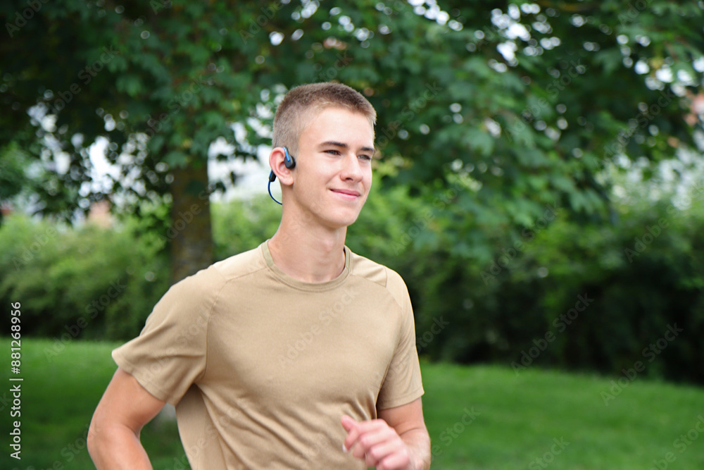 Young man running in urban park, teenager jogging with headphones, in motion Young man running in urban park, teenager jogging with headphones, in motion