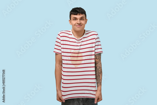 Smiling young man with coffee stains on his t-shirt on blue background