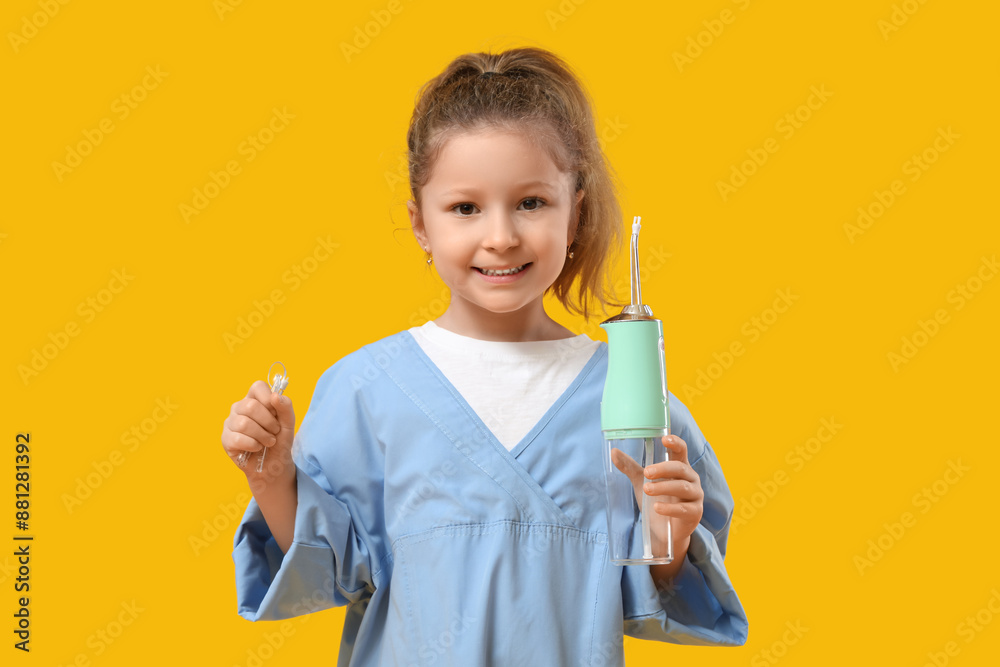 Happy little girl with oral irrigator on yellow background Happy little girl with oral irrigator on yellow background