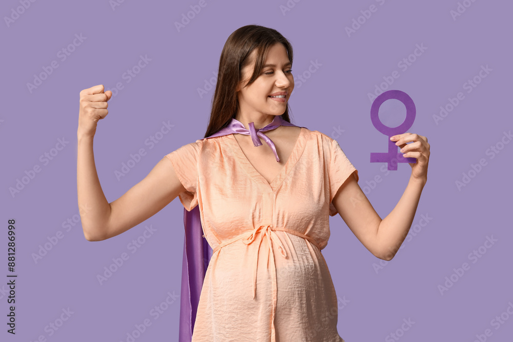 Beautiful young pregnant woman in superhero cape with gender symbol showing muscles on lilac background Beautiful young pregnant woman in superhero cape with gender symbol showing muscles on lilac background