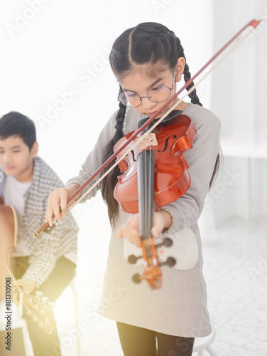 cute asian children playing violin with. friends, she show violin skill and present melody and song to friends, asian children group in musical training time