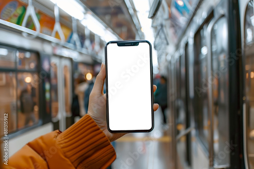 A close-up shot of a hand holding a smartphone with a blank screen inside an orange subway train. photo