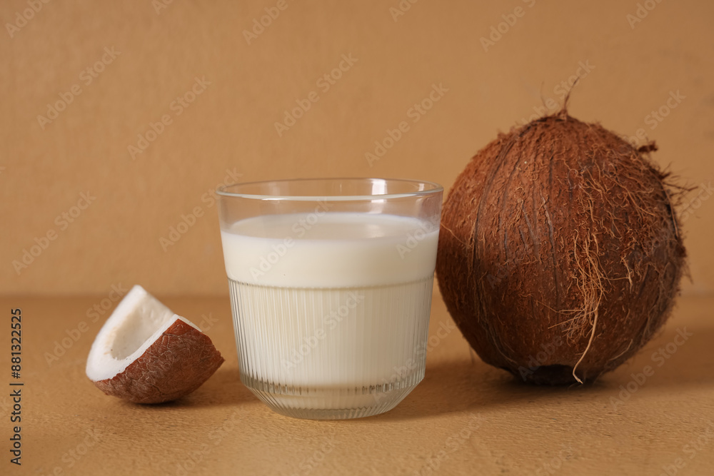 Glass of tasty fresh coconut milk on beige background, closeup