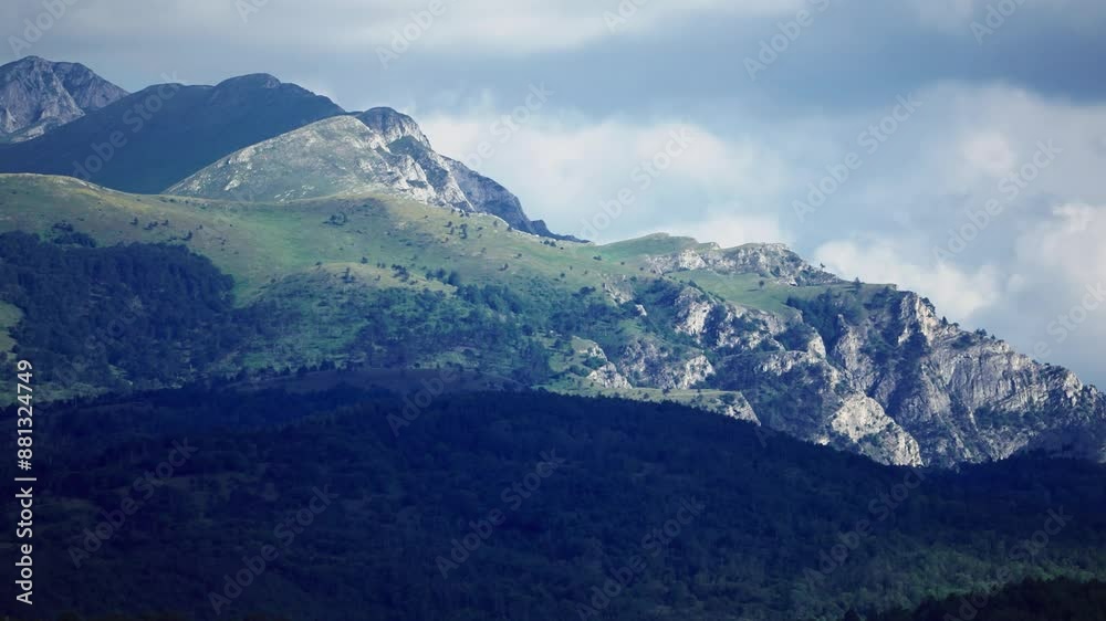 Panoramic view of rocky mountain summit called Solunska Glava in Macedonia on sunny day. The mountains are covered in green grass and trees and the sky is cloudy Panoramic view of rocky mountain summit called Solunska Glava in Macedonia on sunny day. The mountains are covered in green grass and trees and the sky is cloudy