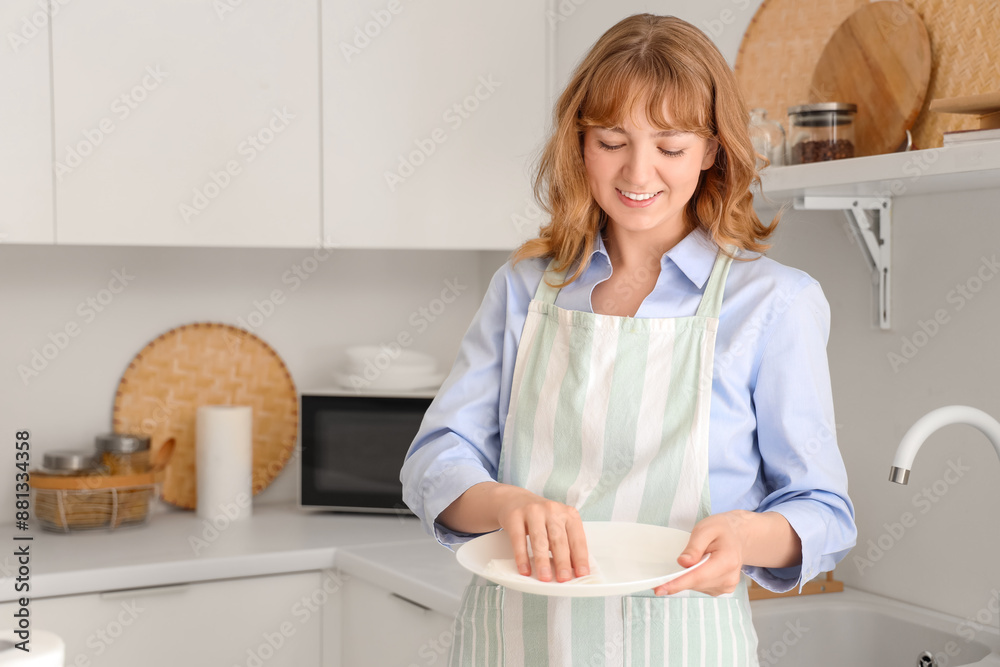Young woman wiping dishware with paper towel in kitchen Young woman wiping dishware with paper towel in kitchen