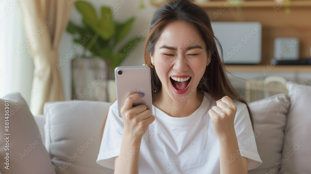 Excited Asian Woman Celebrates Success on Sofa with Smartphone - Isolated White Background - Happy Female Holding Mobile Device - Technology Excited Asian Woman Celebrates Success on Sofa with Smartphone - Isolated White Background - Happy Female Holding Mobile Device - Technology