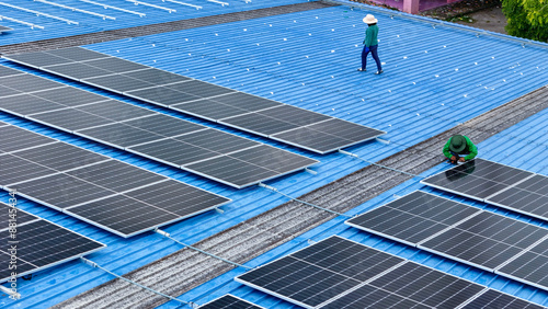 top aerial of engineer men inspects construction of solar cell panel or photovoltaic cell at roof top. Industrial Renewable energy of green power. factory at urban area. worker working on tower roof. photo