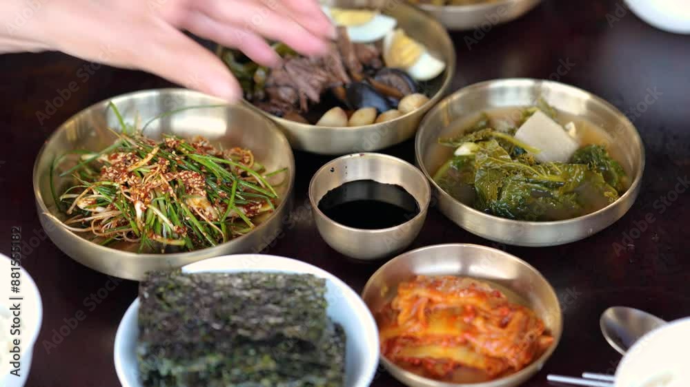 다양한 반찬들이 차려진 테이블 위에 간장을 놓는 손