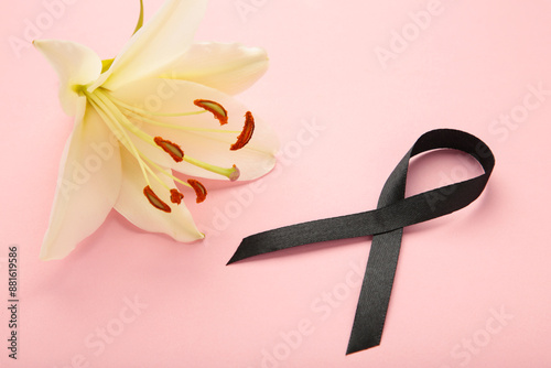 White liles flowers with black ribbon on pink background. Mourning or funeral background photo