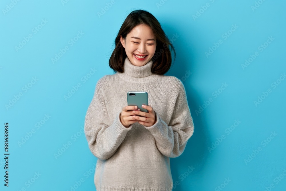 Smiling Young Asian Woman Enjoying Social Media on Smartphone Against Blue Background. Horizontal banner with copy space Smiling Young Asian Woman Enjoying Social Media on Smartphone Against Blue Background. Horizontal banner with copy space