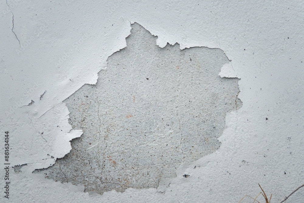 Fototapeta premium A white wall with a hole in it. The wall appears to be old and worn, with some paint peeling off