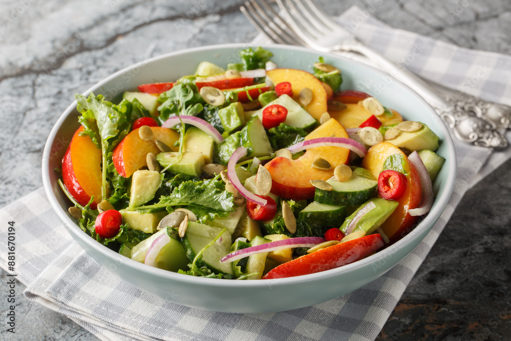 Spicy salad with nectarine, avocado, cucumber, red onion, chili, arugula, spinach and pumpkin seeds close-up in a bowl on the table. Horizontal Spicy salad with nectarine, avocado, cucumber, red onion, chili, arugula, spinach and pumpkin seeds close-up in a bowl on the table. Horizontal