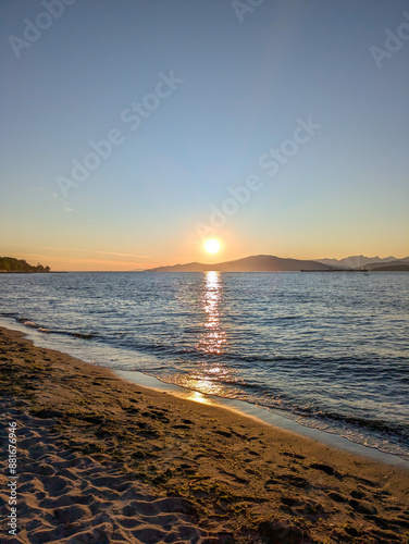 Golden sunset and blue sky over gentle waves lapping on beach in summertime - Jericho Beach, Vancouver British Columbia Canada photo