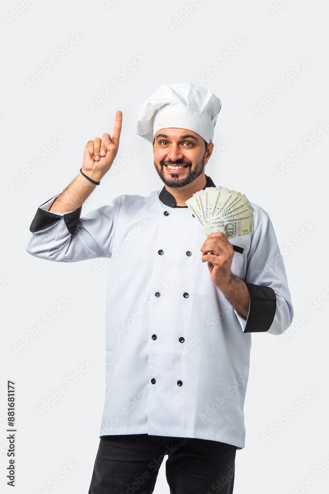 Smiling Asian Indian chef or professional cook with 500 rupee money fan, isolated white background Smiling Asian Indian chef or professional cook with 500 rupee money fan, isolated white background