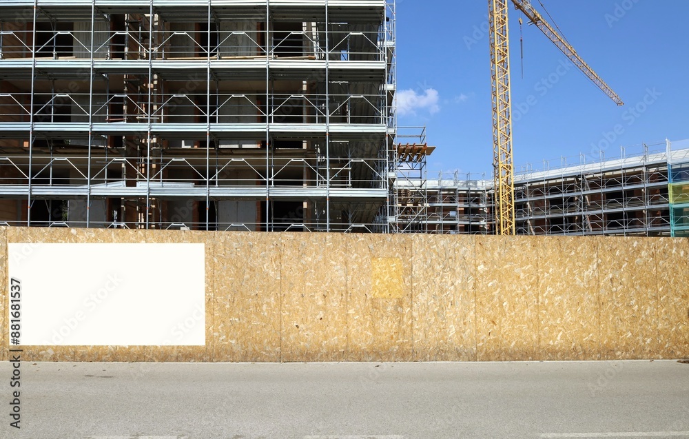 custom made wallpaper toronto digitalBlank information board on fence outside the construction site with a new large building among the scaffolding, Tower crane and sky. Background for copy space.