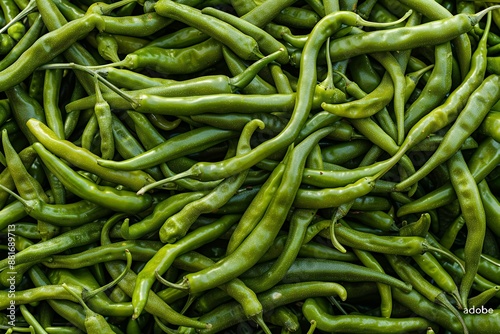 Top view of fresh green chili peppers for background, texture or pattern. Green chilli pile. Top down view of sweet legumes in a natural organic market. Sichuan cuisine with prime hot peppers in the s photo