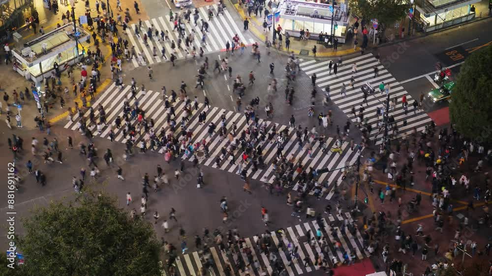 Remarkable pedestrian crossing of Tokyo, time lapse of busy Shibuya intersection at evening hour, view from high point. Car traffic pass by and street crosswalk filled with crowds of people