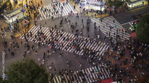 Remarkable pedestrian crossing of Tokyo, time lapse of busy Shibuya intersection at evening hour, view from high point. Car traffic pass by and street crosswalk filled with crowds of people