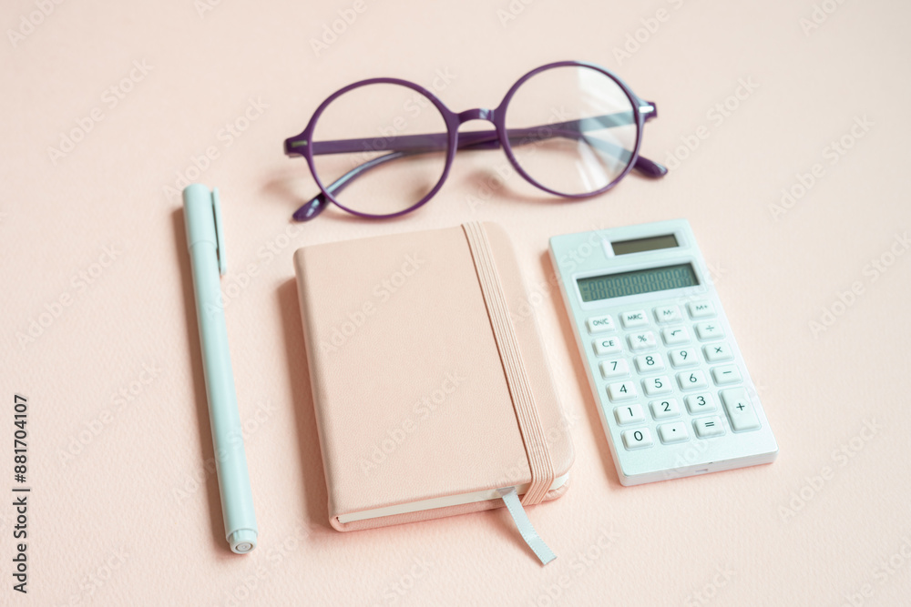 Diary notebook, pen, eyeglasses, calculator on pink desk background