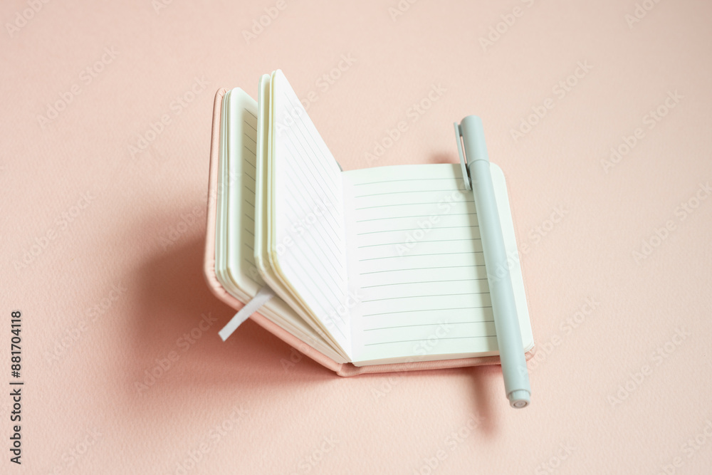 Open lined notebook and pen on pink desk background