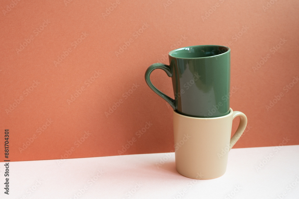 Khaki and beige mug cups on pink table. red background