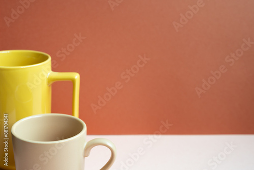 Obraz na płótnie Yellow and beige mug cups on pink table. red background w salonie