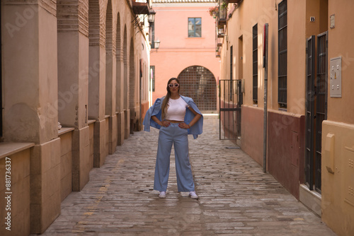 Young and beautiful woman with brown hair, sunglasses and blue jacket suit, with her hands on her waist, empowered and independent, entrepreneur. Concept beauty, fashion, trend.