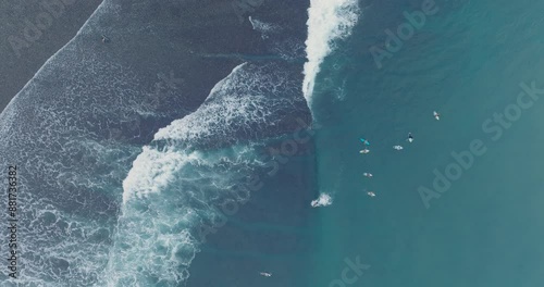 Top Down Slow Motion Drone of surfers waiting for waves at low tide reef with deep blue water at Bingin Beach, Bali, Uluwatu Indonesia