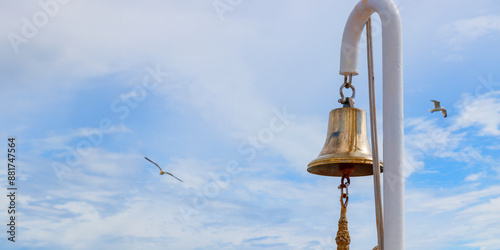 Ship's bell on a white mast against a blue sky with seagulls, sea travel, ocean vacation photo