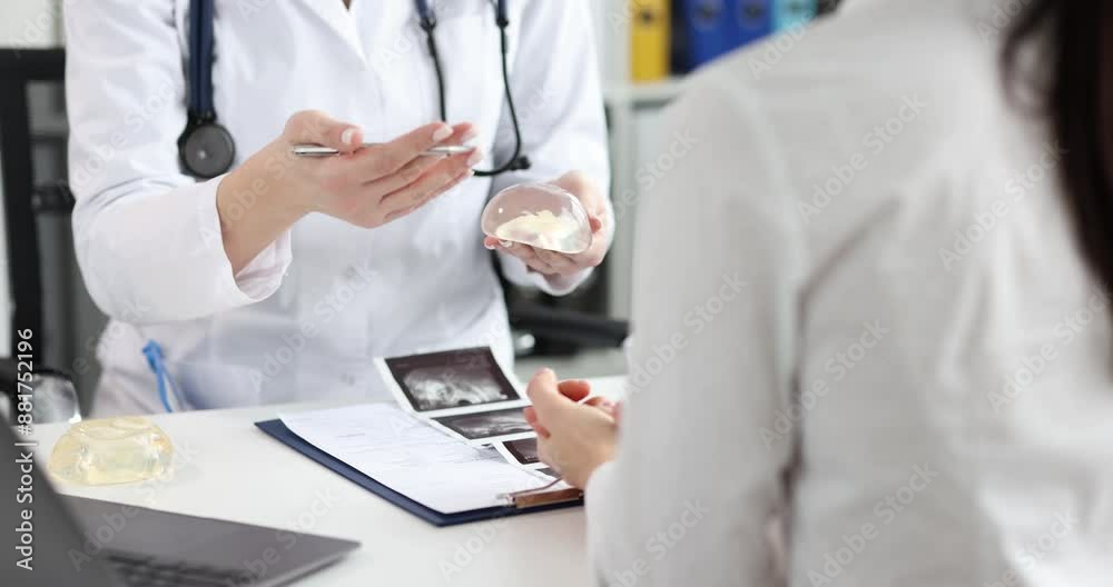 Patient examining silicone breast implants during appointment with plastic surgeon. Mammoplasty and plastic surgeon consultation concept Patient examining silicone breast implants during appointment with plastic surgeon. Mammoplasty and plastic surgeon consultation concept