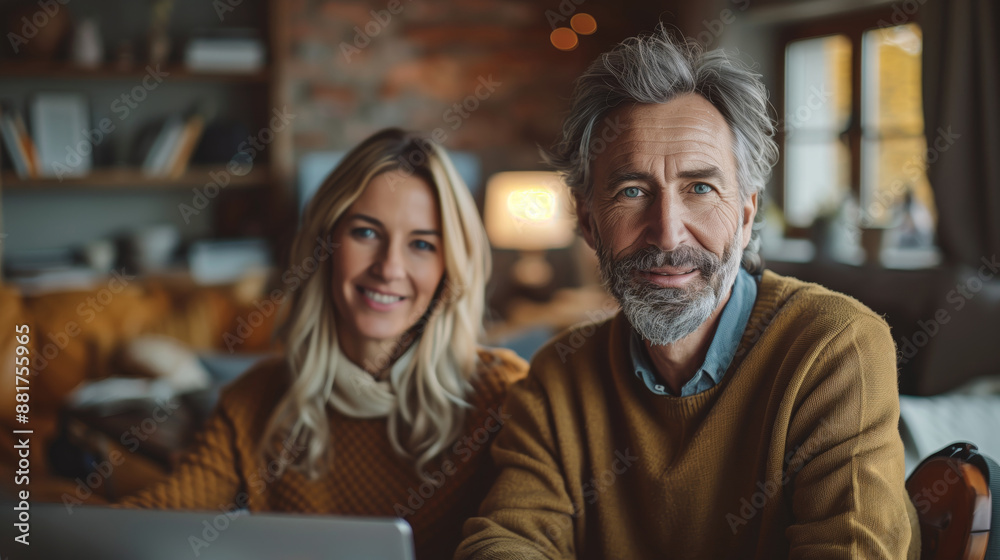 Fototapeta premium Happy Mature Couple in Cozy Living Room. Happy mature couple sitting together in a cozy living room, smiling and enjoying each other's company.