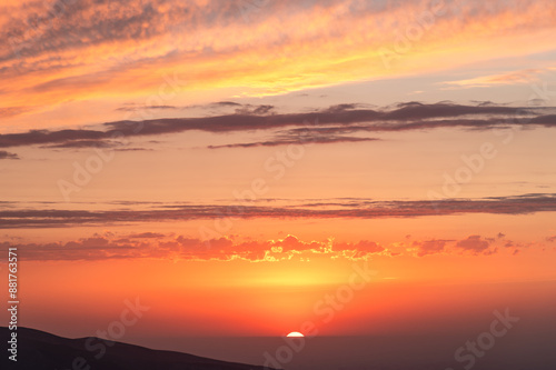 Silhouettes of mountains at sunset and the falling sun, amazing sky. Tranquility and beauty of nature. Selective focus.