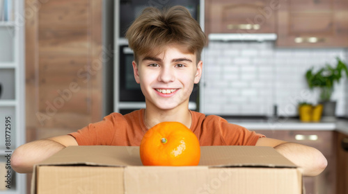 Teen boy helps lowincome families by packing donations at home for charity. Sustainable living practice. photo