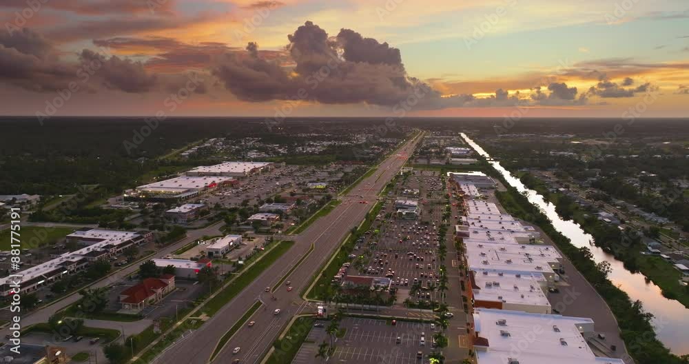 Shopping plaza stores and malls at sunset and American wide highway with many driving cars in North Port, Florida. USA retail and transportation infrastructure. Shopping plaza stores and malls at sunset and American wide highway with many driving cars in North Port, Florida. USA retail and transportation infrastructure.