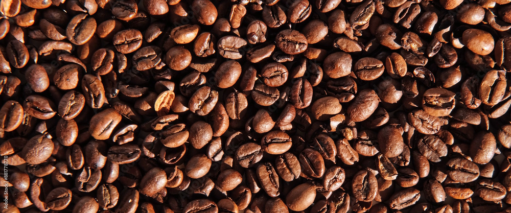 Obraz premium Coffee beans banner background. Texture of coffee beans close up. Dark brown roasted coffee is spinning. Abundance. Concept for coffee product advertising. Selective Focus. Border design, copy space