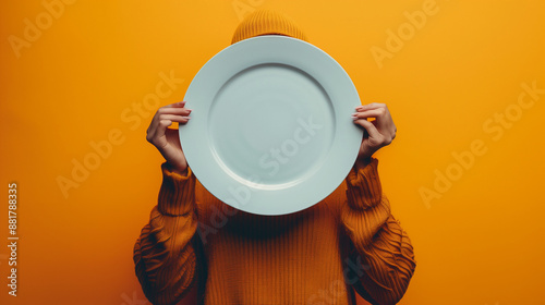 Image of hands holding empty plate, symbolizing food insecurity against vibrant backdrop.

