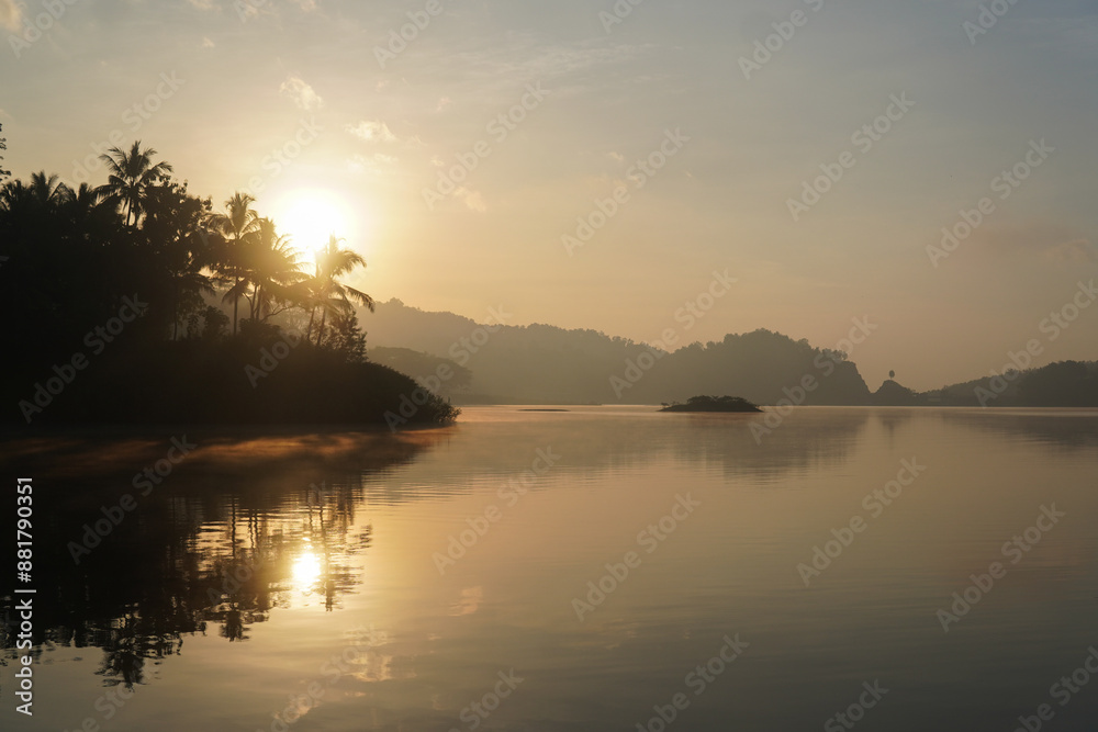 Obraz premium A beautiful morning view of sunrise over Sermo lake in Yogyakarta with a mountain in the background.