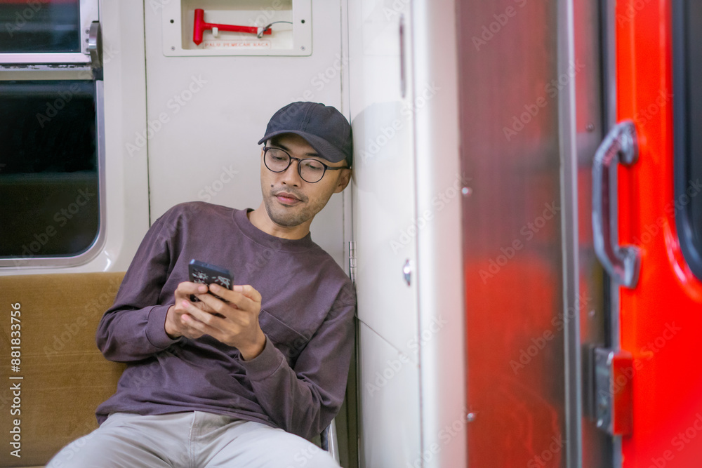Asian Man leaning in the train while using mobile phone Asian Man leaning in the train while using mobile phone