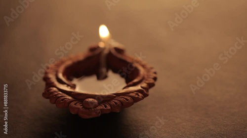 A backlit earthen oil lamp being lit by a male hand during Diwali, creating a warm and festive atmosphere.