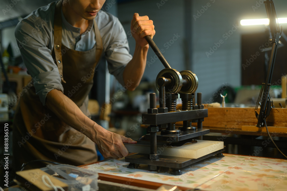Leather craftsman working with manual leather die cutting machine in his workshop. Leather craftsman working with manual leather die cutting machine in his workshop.
