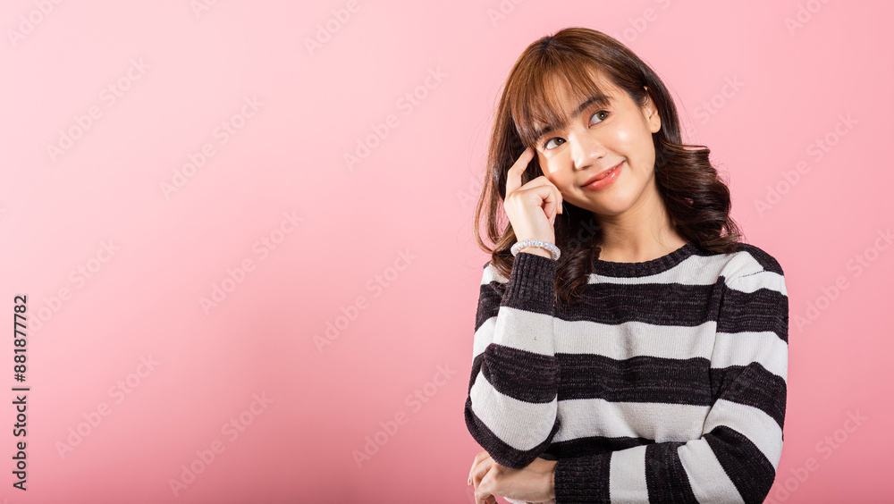 Portrait of a contemplative Asian woman, standing with her chin in her hand, thinking about a question. Studio shot on pink with ample copy space, showing her intelligent look. Portrait of a contemplative Asian woman, standing with her chin in her hand, thinking about a question. Studio shot on pink with ample copy space, showing her intelligent look.