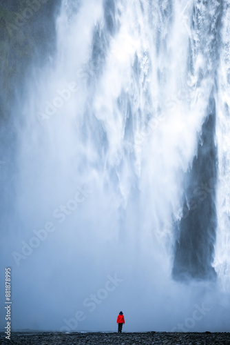 Obraz na płótnie Stunning view of the Skógafoss Waterfall with a tourist wearing a red jacket. Skógafoss is one of the biggest waterfalls in Iceland, situated on the Skoga River in the south of Iceland. w salonie